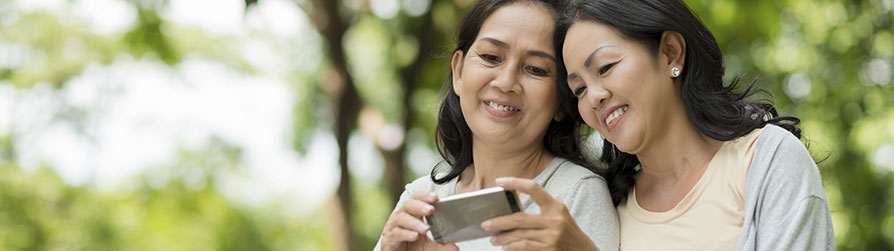 Adult Mom and adult daughter staring at cell phone