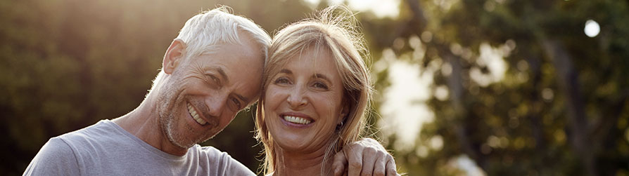 Senior couple hugging outside looking at camera