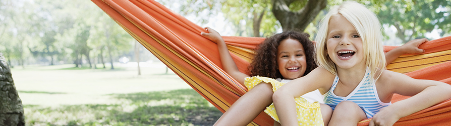 Two young girls on a hammock smiling at the camera